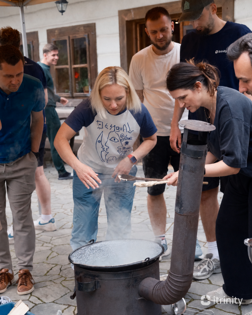 itrinity team members cooking halušky in a large pot outdoors